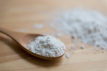 Fototapeta na wymiar Close-up of tapioca starch or flour powder in wooden spoon with wooden background