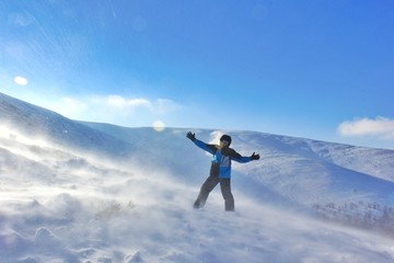 Naklejka na ściany i meble Man on top of mountain in blizzard 