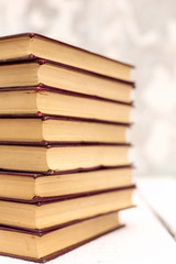 Stack of old ancient shabby books on a white wooden background.