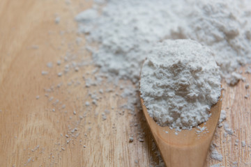 Close-up of tapioca starch or flour powder in wooden spoon with wooden background