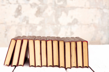 Stack of old ancient shabby books on a white wooden background.