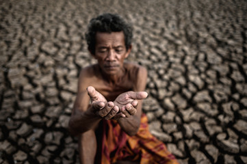 An elderly man was sitting asking for rain in the dry season, global warming, selective focus
