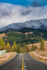Scenic drive with empty asphalt road in south island New Zealand with a view of trees and mountain.