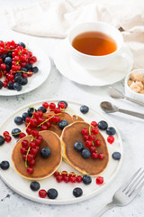 Sweet pancakes with red currants and blueberries. Wholesome breakfast