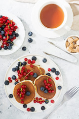 Sweet pancakes with red currants and blueberries. Wholesome breakfast