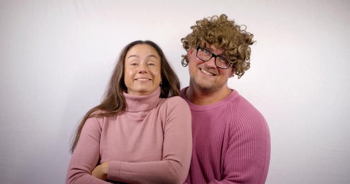pretty woman and her cheerful boyfriend with funny curly wig on head are smiling broadly
