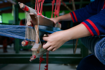 Cotton weaving. Woman hand weaving cotton in traditional way at manual loom. Traditional thailand cotton. Selective focus.