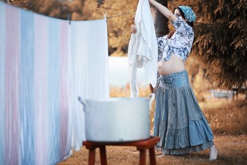 Pregnant woman hanging sheets on the rope for drying