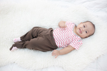 happy baby lying on white bed