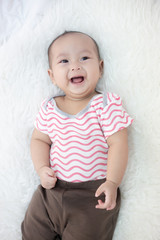 happy baby lying on white bed
