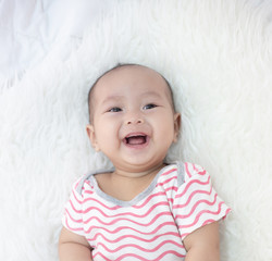 happy baby lying on white bed