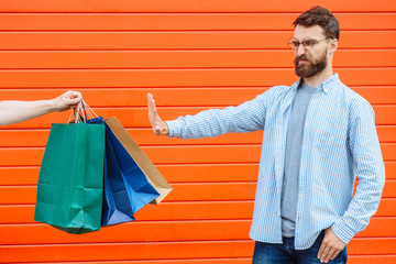 Thanks but no- man expressing his refusal with stopping hand gesture, blue studio background