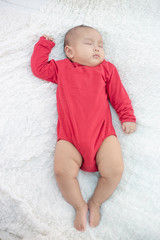 Babies wearing red shirts sleeping in bed
