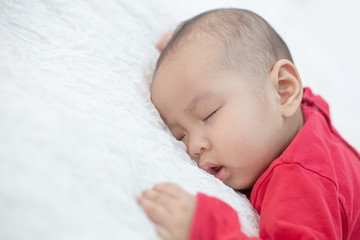 Babies wearing red shirts sleeping in bed