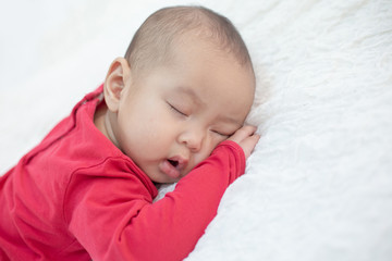 Babies wearing red shirts sleeping in bed