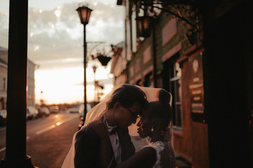 Bride and groom hugging in the town street. Interracial marriage. Asian bride and groom.