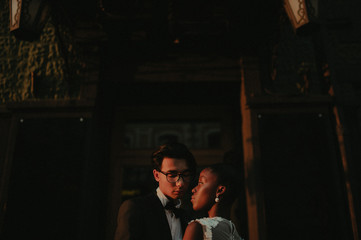 Fototapeta na wymiar Bride and groom hugging in the town street. Interracial marriage. Asian bride and groom.