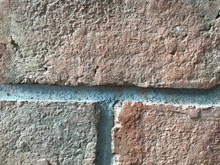 A close up on brown earth tone brick wall texture showing the roughness and details of clay brick