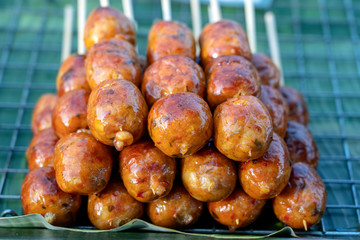 Grilled Thai sausage at street food market in Thailand, closeup. Traditional Thai sausage with pork and rice, delicious street food