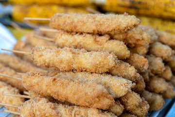 Skewers with fried chicken wings in batter for sell in street food market, Thailand, closeup