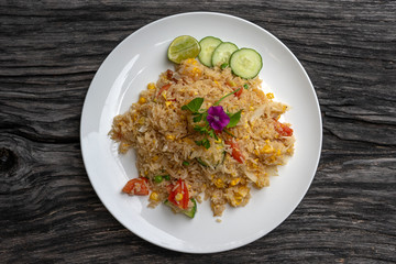 Fried rice with shrimps and vegetables in a white dish on an old wooden table, close up . Thai food , Thai cuisine