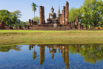 Fototapeta na wymiar View of the sculpture of a sitting Buddha on the ruins of the Buddhist temple Wat Chana Songkram on a sunny day. Sukhothai Historical Park, Thailand