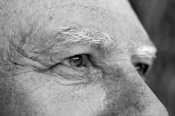 Fototapeta premium Closeup eye of caucasian old man. Portrait of old man outdoors. Caucasian male face background, close up eyes, macro, black and white