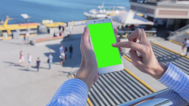 Hight quality 10bit footage of Young woman uses SmartPhone with green screen staying in city square. Made from 14bit RAW