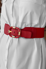 Cropped close-up shot of a lady dressed in a white buttoned shirt with pockets and a wide red...
