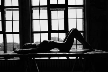 Schwarz-Weiß-Porträt einer sexy, schönen jungen Dame über hellem Fensterhintergrund © spritnyuk