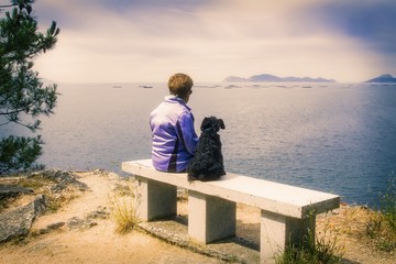 lonely woman with her dog looking at the sea