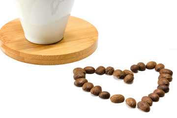Roasted coffee beans background texture in the shape of a hearth with a cup behind it, isolated on white background with space for text