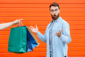 hand holding and giving many colorful shopping bags to the man isolated on a white background