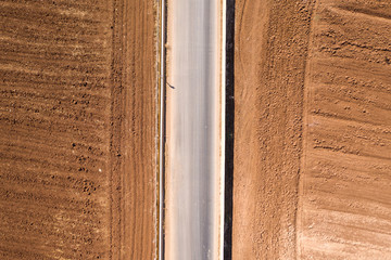 Asphalt road with deep brown soil on both sides, Top down aerial image.