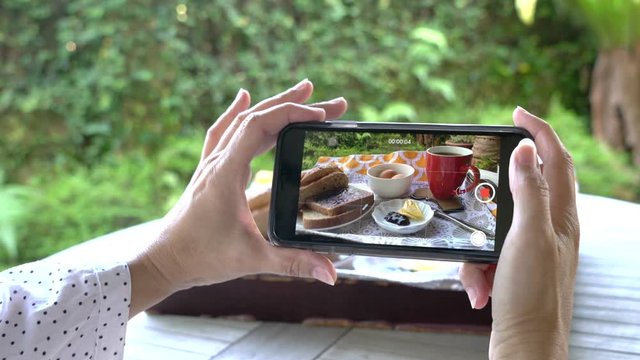 Woman hands taking video of her breakfast with her smartphone. Closeup. Social media, documenting the food before eating concept.