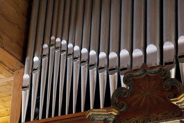 Pipe organ frontal shot, shiny silver prospect pipes pattern, row closeup. Sacral music, church musical service and classical organ concert poster concept. Old pipe organ in a small wooden church