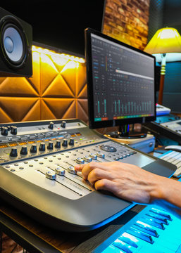 sound engineer hand adjusting volume level on audio mixing console in recording, broadcasting studio