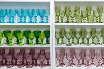 Colorful glasses and vases on the shelf in the souvenir shop. wine glasses stand on the shelves in a large supermarket