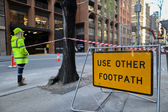 Use other footpath traffic warning sign barrier applying on busy street downtown on pedestrian footpath, road under construction defocused traffic controller on side road Sydney city CBD, Australia 
