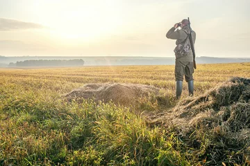 Foto op Canvas Hunting period, autumn season. Male with a gun looking in binoculars. Hunter man. © Sergey