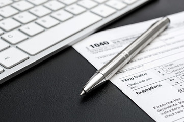 Tax form with computer keyboard and pen at workplace.