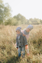 little girl with little brother in the autumn on the nature in the park