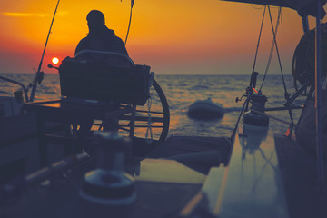 Sailor using wheel to steer rudder on a sailing boat.