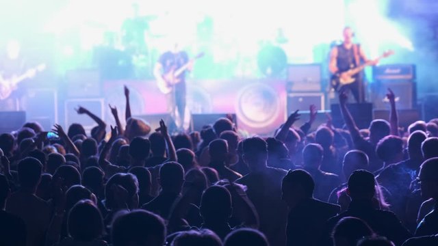 Crowd of fans are cheering at open-air rock concert