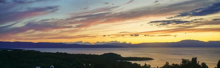 Obraz premium Colorful sunset on the Adriatic coast. Cres island and Istrian mountains are visible on the horizon