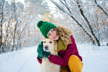 Young woman in winter park walking with her dog. Friendship, pet and human. woman playing with dog outdoors