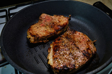 Two pieces of beef fried in a black skillet grill. Grill meat pan. Cooking a beef steak. 