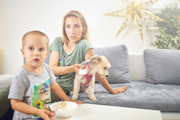 Single mom with TV remote, kid and dog in the living room.