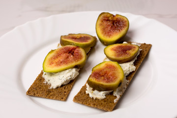 Homemade wheaten bread sliced and topped with cream cheese and fresh figs