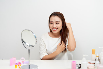 Portrait of brunette woman looking at her face in mirror